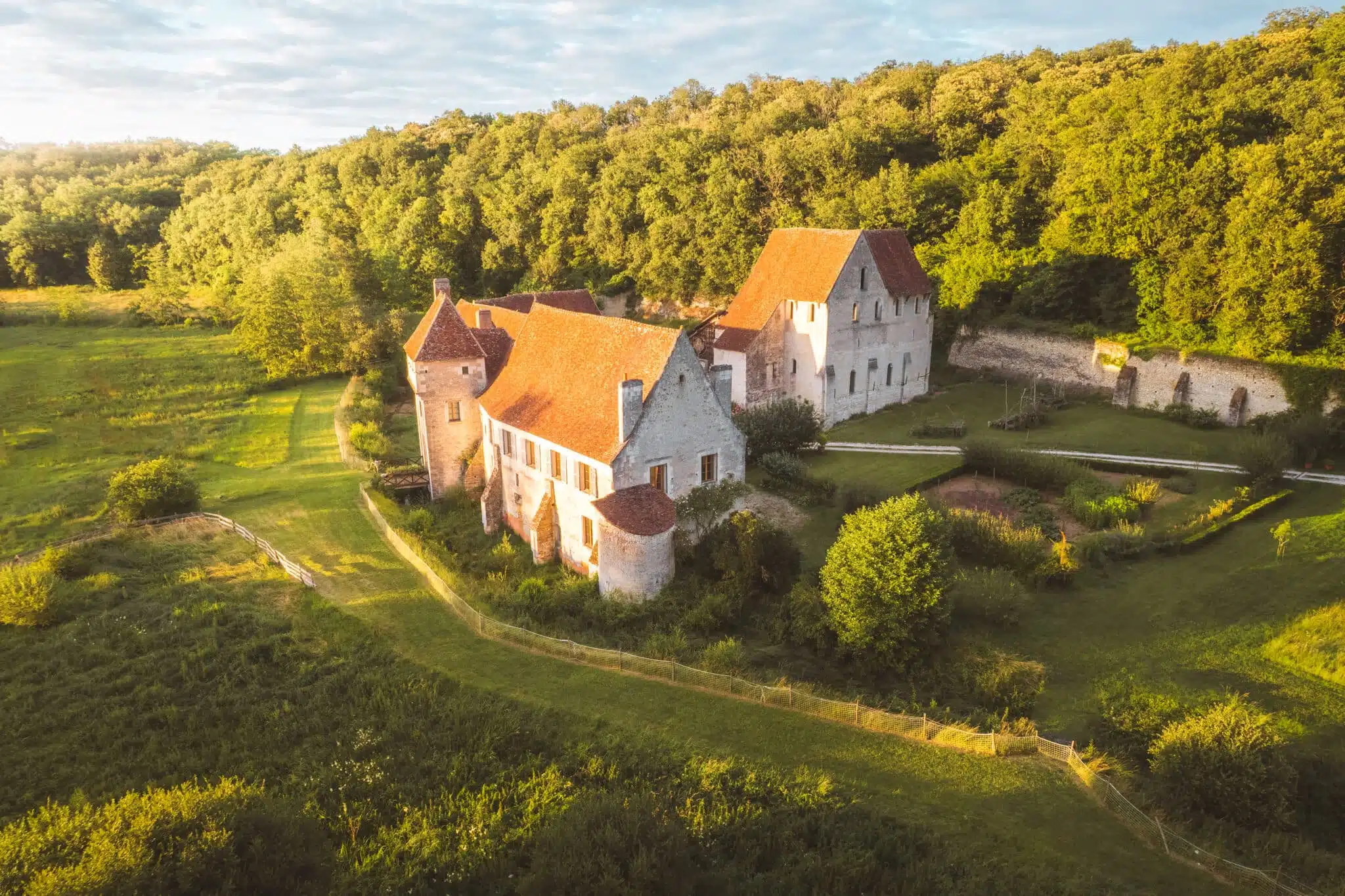 Vue aérienne du Château-monastère de la Corroirie au coucher du soleil, entouré de nature